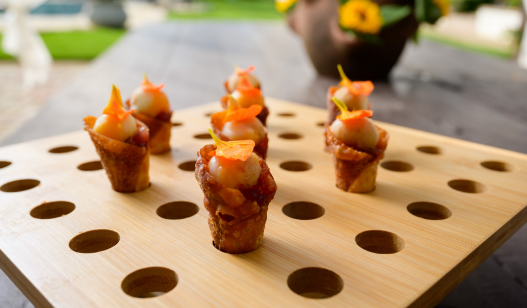 A wooden tray with appetizers on it, perfect for an In-Home Chef Experience.