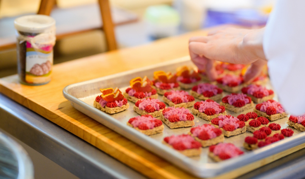 A private chef delicately placing desserts on a tray.