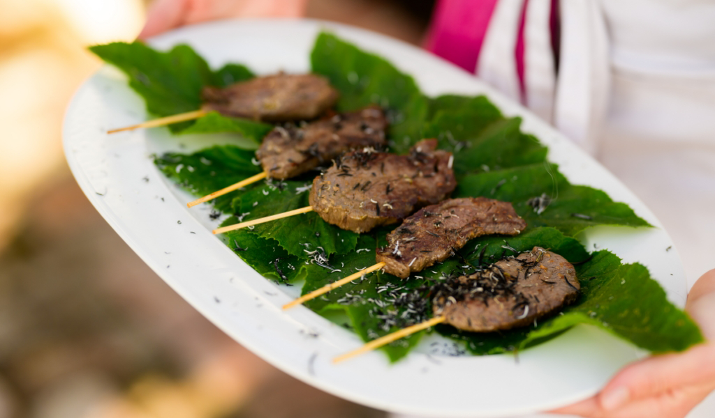 A plate with meat skewers on it, prepared by a private chef for a birthday party.