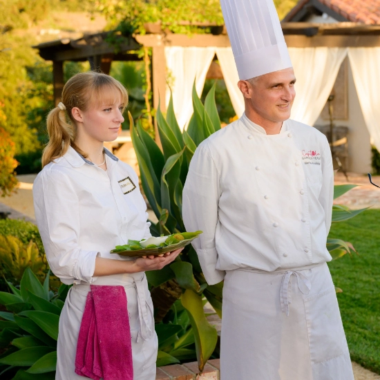 A man and woman wearing chef's outfits, offering private chef services for hire and catering for corporate events.
