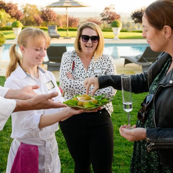 A group of people enjoying a Private Chef for Hire experience as they hold a plate of food in front of a pool.