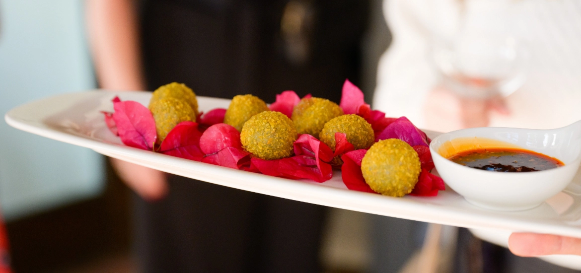 A private chef for hire is expertly holding a plate of food with a delectable sauce on it.